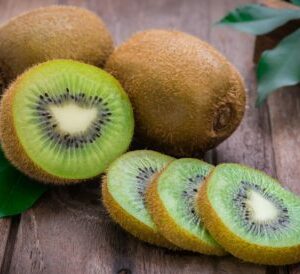 Kiwis entiers et découpés présenté sur une table en bois
