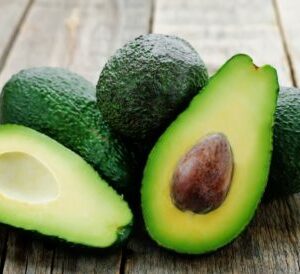 Avocats entiers et coupée en deux sur une table en bois