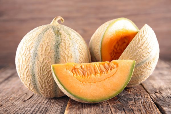 Melons charentais présentés avec une tranche, présentés sur une table en bois - fruit frais